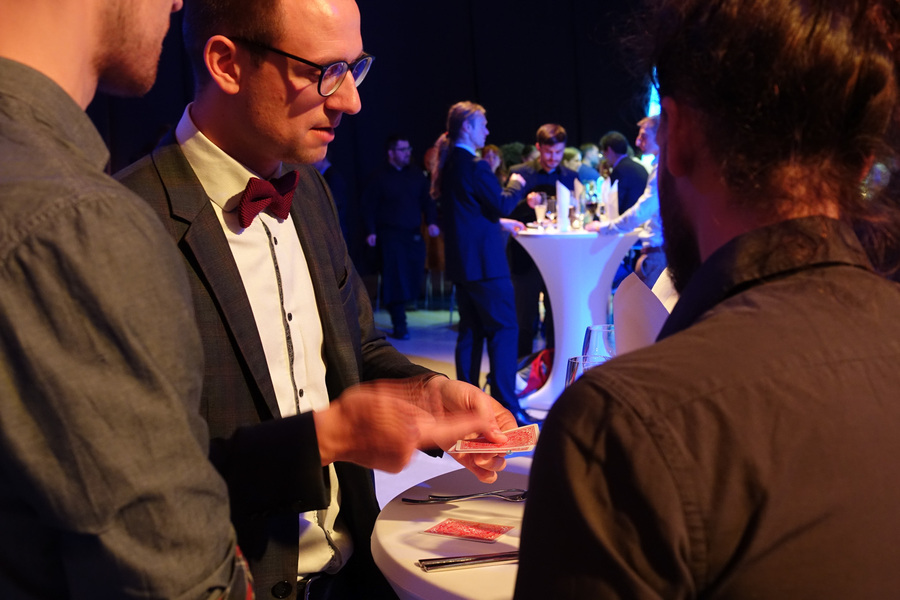 Zauberkünstler am Tisch mit den Teilnehmenden